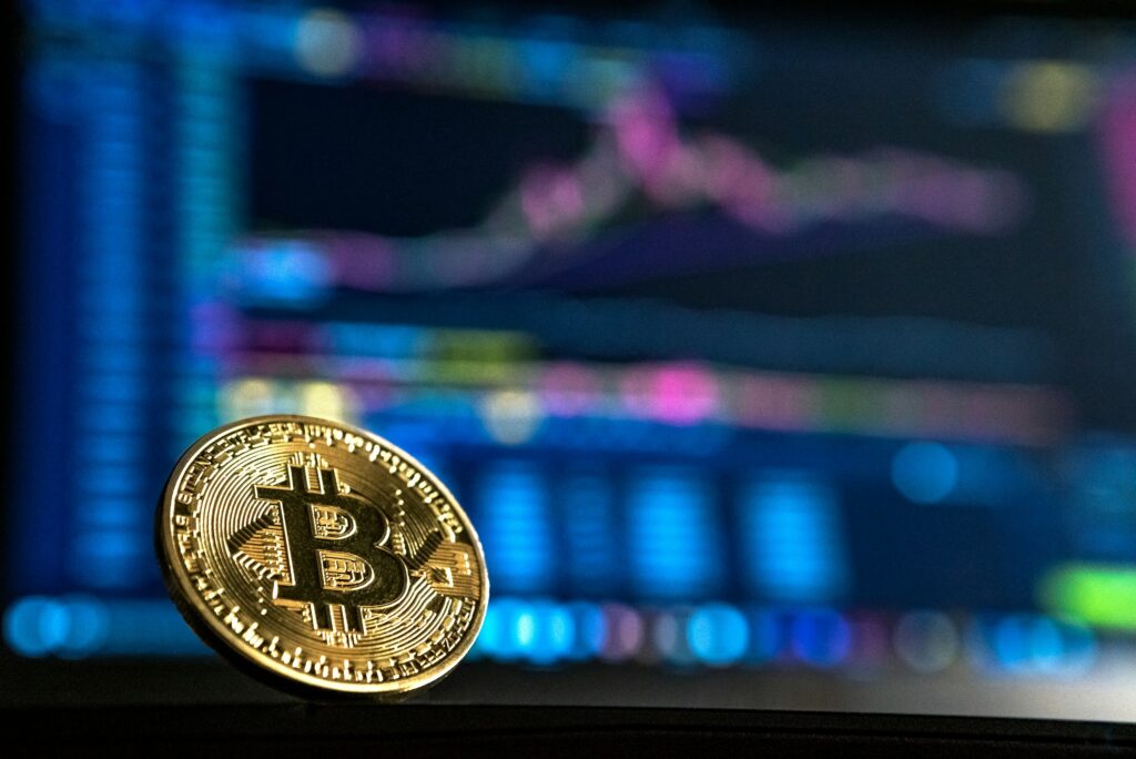 A Legal Guide to Dividing Cryptocurrency and Digital Assets in a California Divorce 1 A physical Bitcoin coin in the foreground with a blurry cryptocurrency price chart displayed on a screen in the background, highlighting the complexities of managing digital assets during a California cryptocurrency divorce.