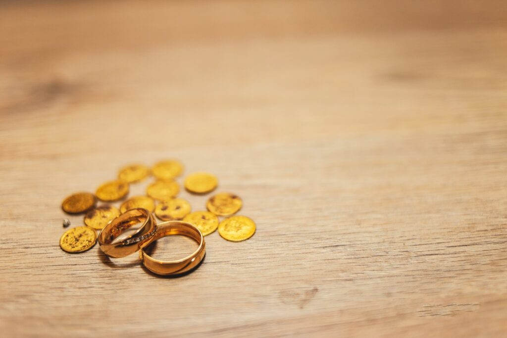 How to Protect Your Retirement Savings in Divorce: 401(k)s, IRAs, and Pensions in California 1 Two gold rings and several small gold coins, often representing retirement savings, are placed on a wooden surface in California.