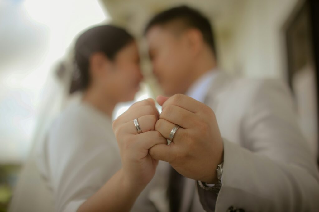 Challenging an Unfair Prenuptial Agreement in California 1 A couple wearing wedding rings holds hands with interlocked pinkies; their faces are out of focus and close together in the background, hinting at their bond despite challenging times, such as facing an unfair prenuptial agreement in California.