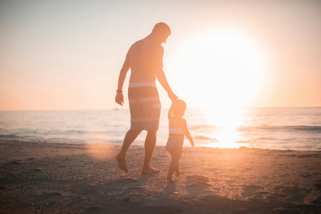 4 Things Parents Wish They Understood About Custody Before Divorce in California 1 An adult and a child walk along a sandy beach at sunset, the sun low over the ocean in the background—a peaceful moment reflecting on parental rights and custody in California.