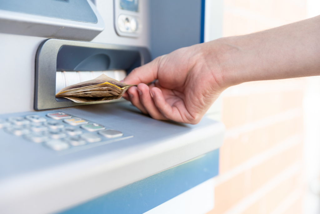 A hand withdrawing cash from an ATM, a common action involving asset division during a California divorce.