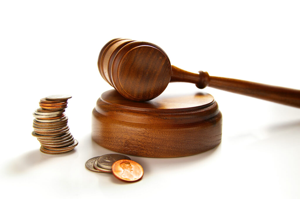 judges court gavel and assorted coins, on white